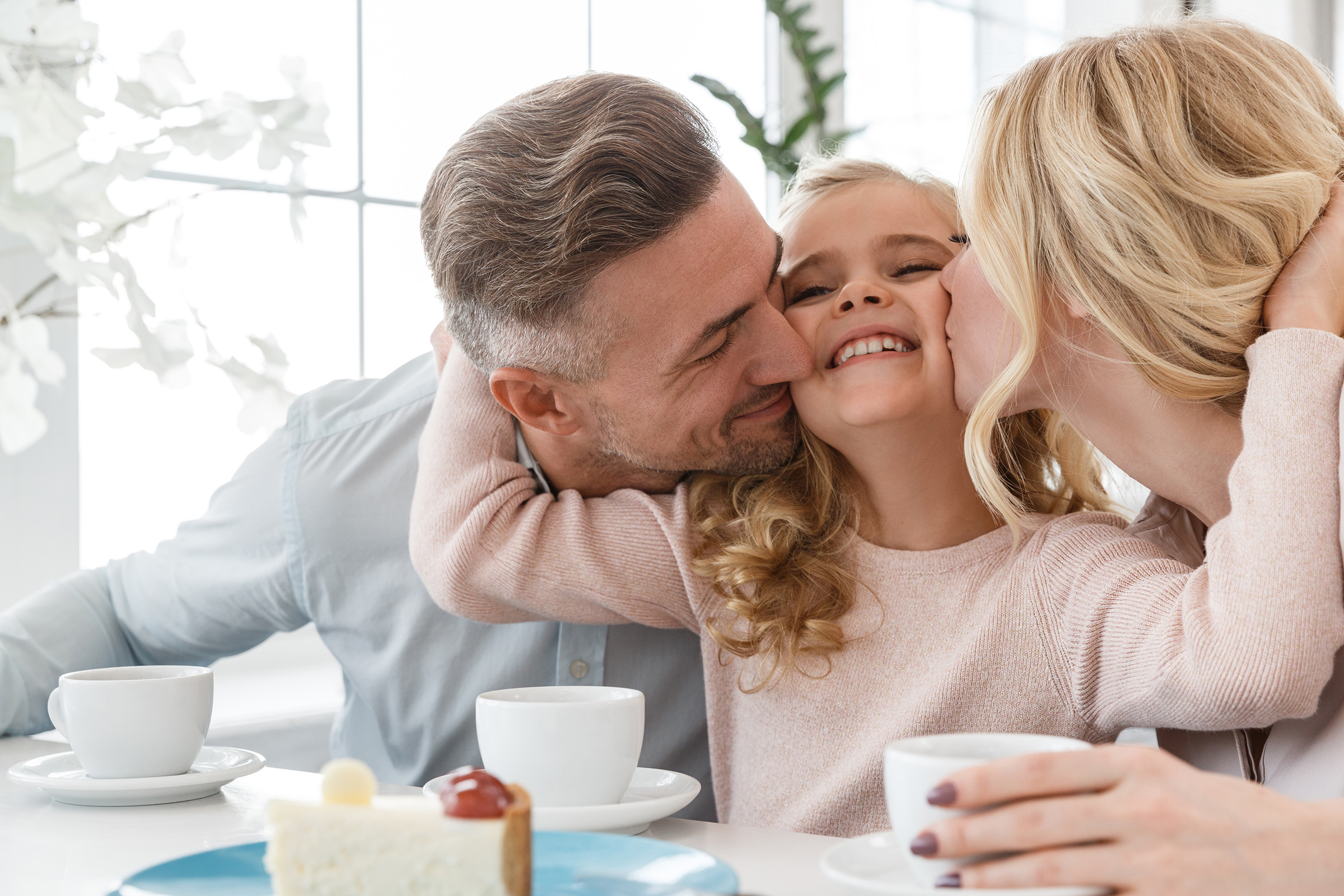 couple kissing their daughter