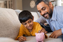 father and child inserting coin to piggy bank